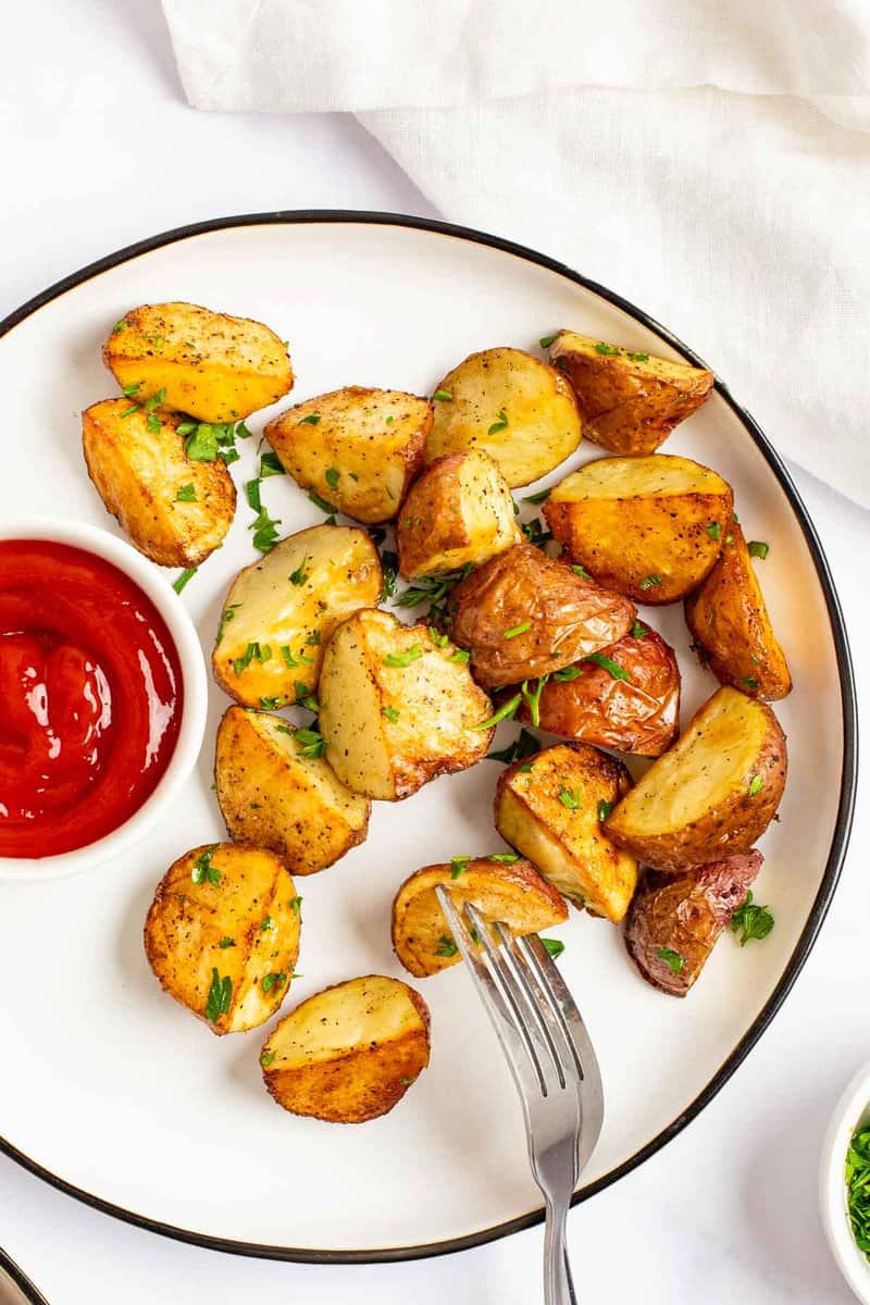 Oven roasted red potatoes and ketchup on a plate.