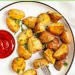 Oven roasted red potatoes and ketchup on a plate.