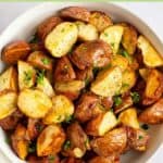 A bowl of oven roasted red potatoes garnished with fresh parsley.