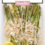 Sauteed asparagus spears with lemon cream sauce and lemon slices on a serving platter.
