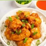 Sweet and sour chicken over white rice in a bowl.