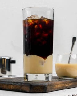 Vietnamese iced coffee in a tall glass and a small bowl of sweetened condensed milk.