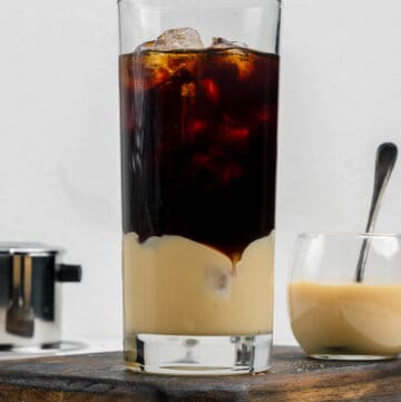 Vietnamese iced coffee in a tall glass and a small bowl of sweetened condensed milk.