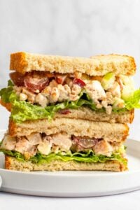 Copycat Arby's pecan chicken salad sandwich halves stacked on a plate.
