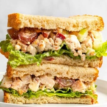 Copycat Arby's pecan chicken salad sandwich halves stacked on a plate.