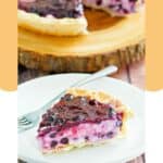 A slice of homemade blueberry cream cheese pie and a fork on a plate.