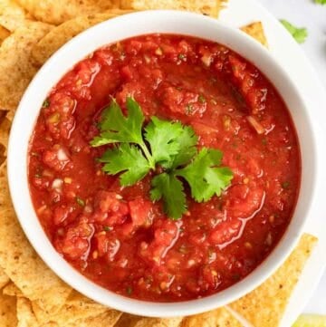 A bowl of copycat Chili's salsa and tortilla chips on a platter.