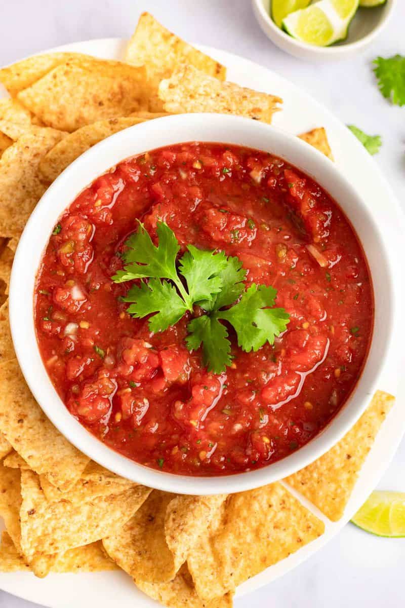A bowl of copycat Chili's salsa and tortilla chips on a platter.