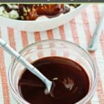 Homemade Hershey's syrup and a spoon in a small bowl.