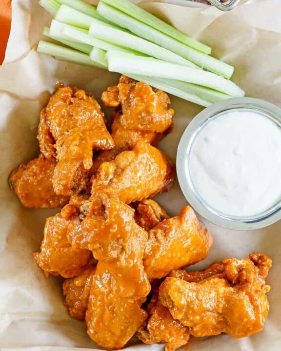 Copycat Hooters wings, a small cup of dipping sauce, and celery sticks.