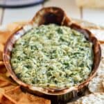 Copycat Houston's spinach artichoke dip on a platter with pita chips and crackers.