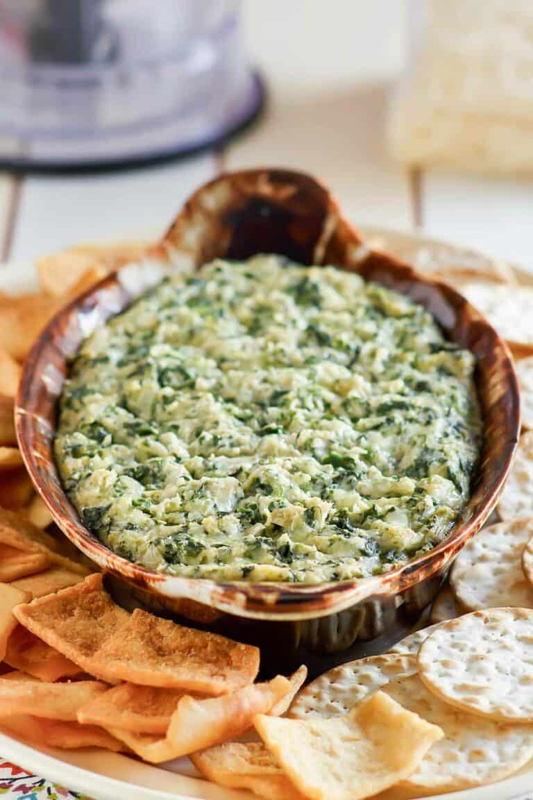 Copycat Houston's spinach artichoke dip on a platter with pita chips and crackers.