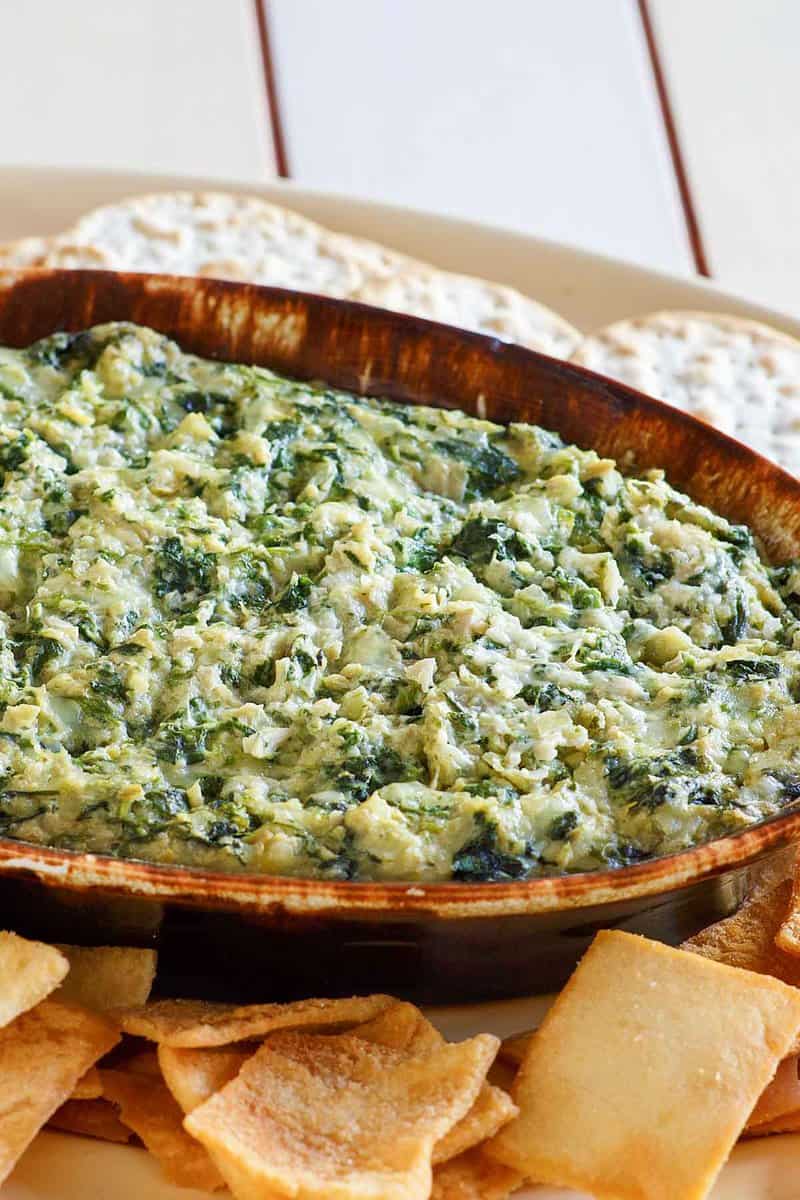 Copycat Houston's spinach artichoke dip, pita chips, and crackers on a tray.