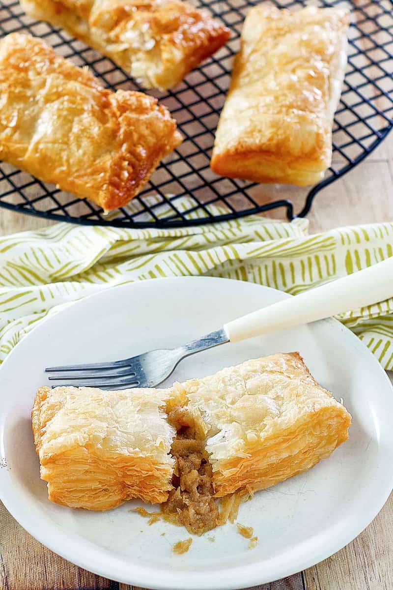 Copycat McDonald's apple pies on a wire rack and one on a plate.