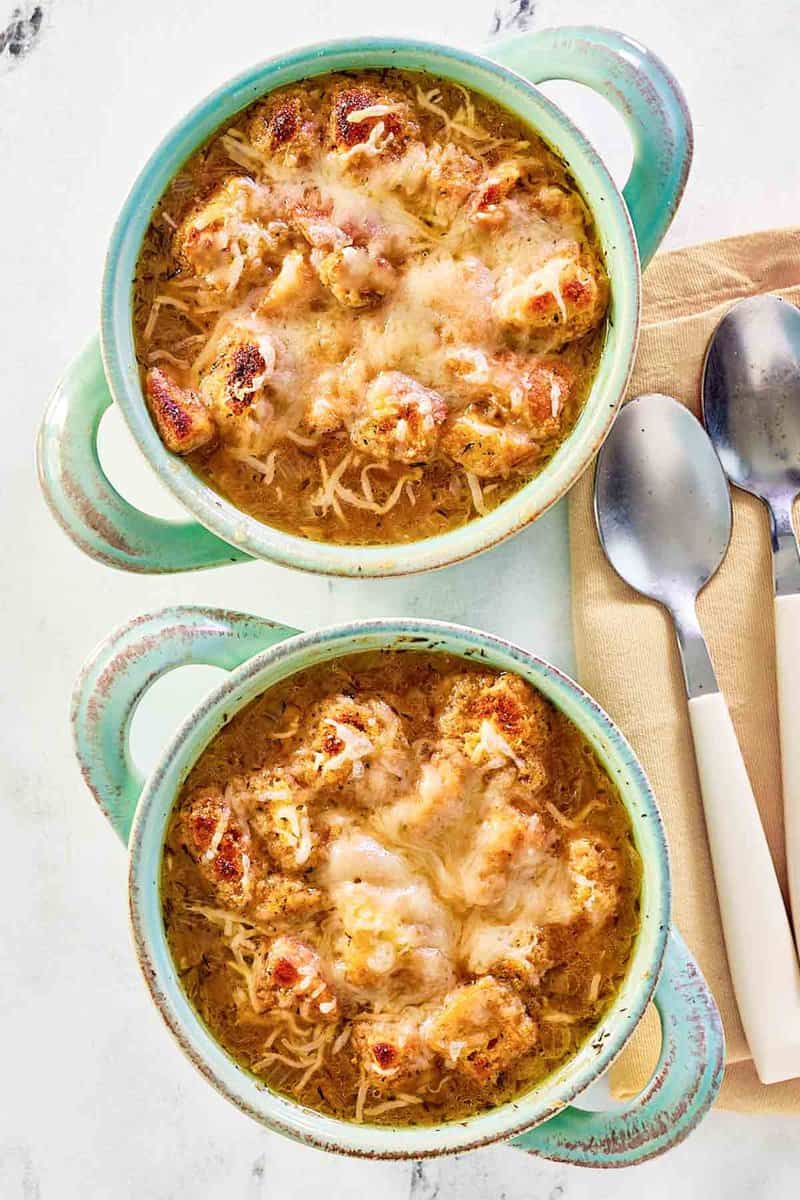 Two bowls of copycat Panera French onion soup and two spoons.