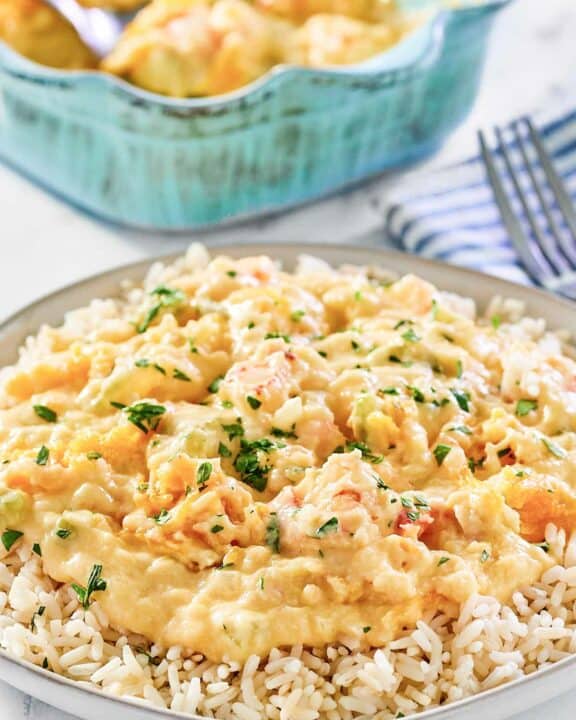 Shrimp and crab au gratin over rice on a plate.