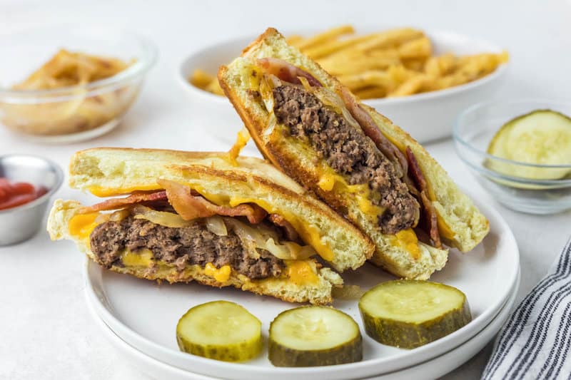 Copycat Waffle House Texas bacon patty melt halves and pickles on a plate.