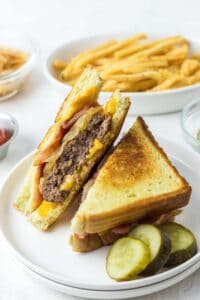 Copycat Waffle House Texas bacon patty melt on a plate and a bowl of fries.
