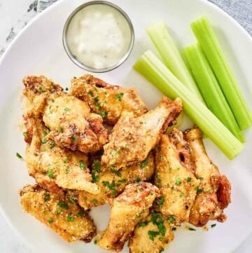 Copycat Wingstop garlic parmesan wings, cup of dipping sauce, and celery sticks.