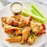 Copycat Wingstop ail  parmesan wings, celery sticks, and a cupful  of dipping sauce.