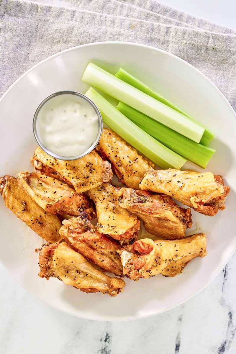 Copycat Wingstop lemon pepper wings, celery sticks, and a cup of dipping sauce.