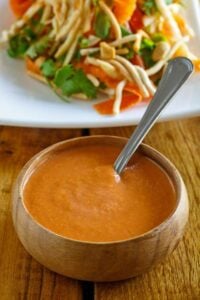 Copycat Benihana ginger salad dressing in a bowl and a salad behind it.