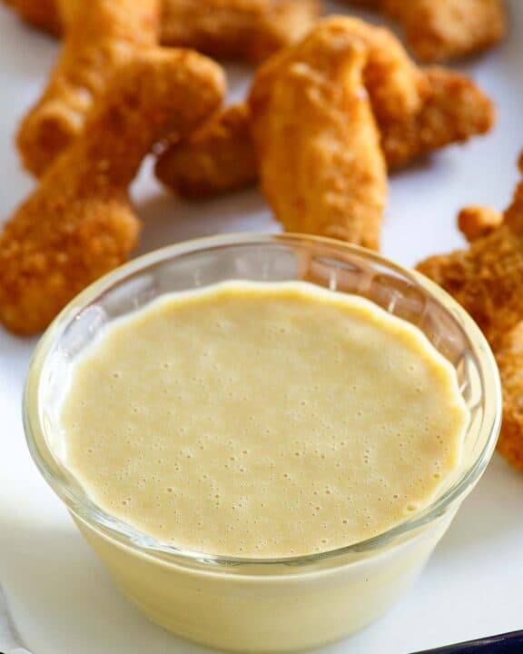 Copycat Outback Steakhouse honey mustard in a bowl and chicken fingers behind it.