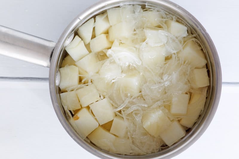 Potatoes, onions, and water in a saucepan.