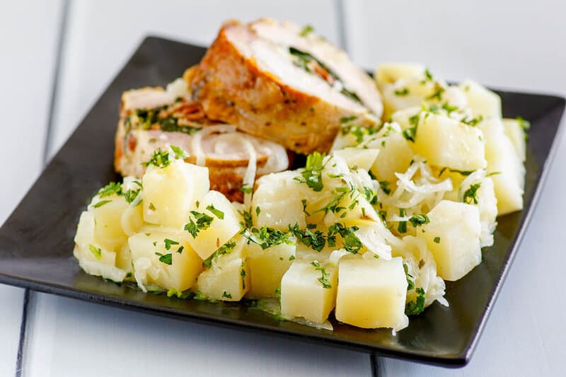 Parsley potatoes and stuffed pork loin slices on a plate.