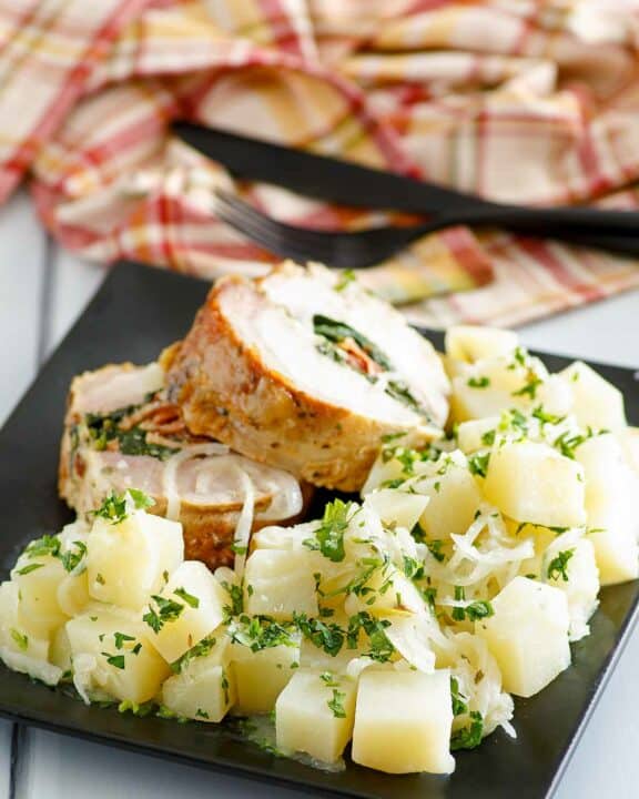 Buttery parsley potatoes and stuffed pork loin slices on a plate.