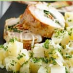 Stuffed pork loin and parsley potatoes with onions on a plate.