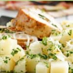 Parsley potatoes on a plate with pork loin slices.