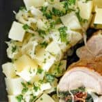Parsley potatoes with onions and pork loin on a plate.