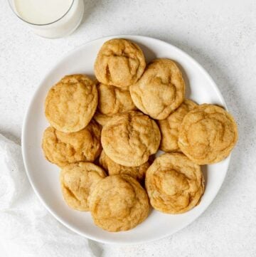 A plate of homemade snickerdoodle cookies and a glass of milk beside it.