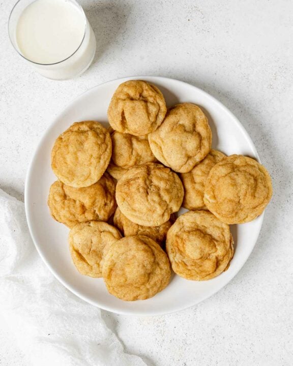 A plate of homemade snickerdoodle cookies and a glass of milk beside it.