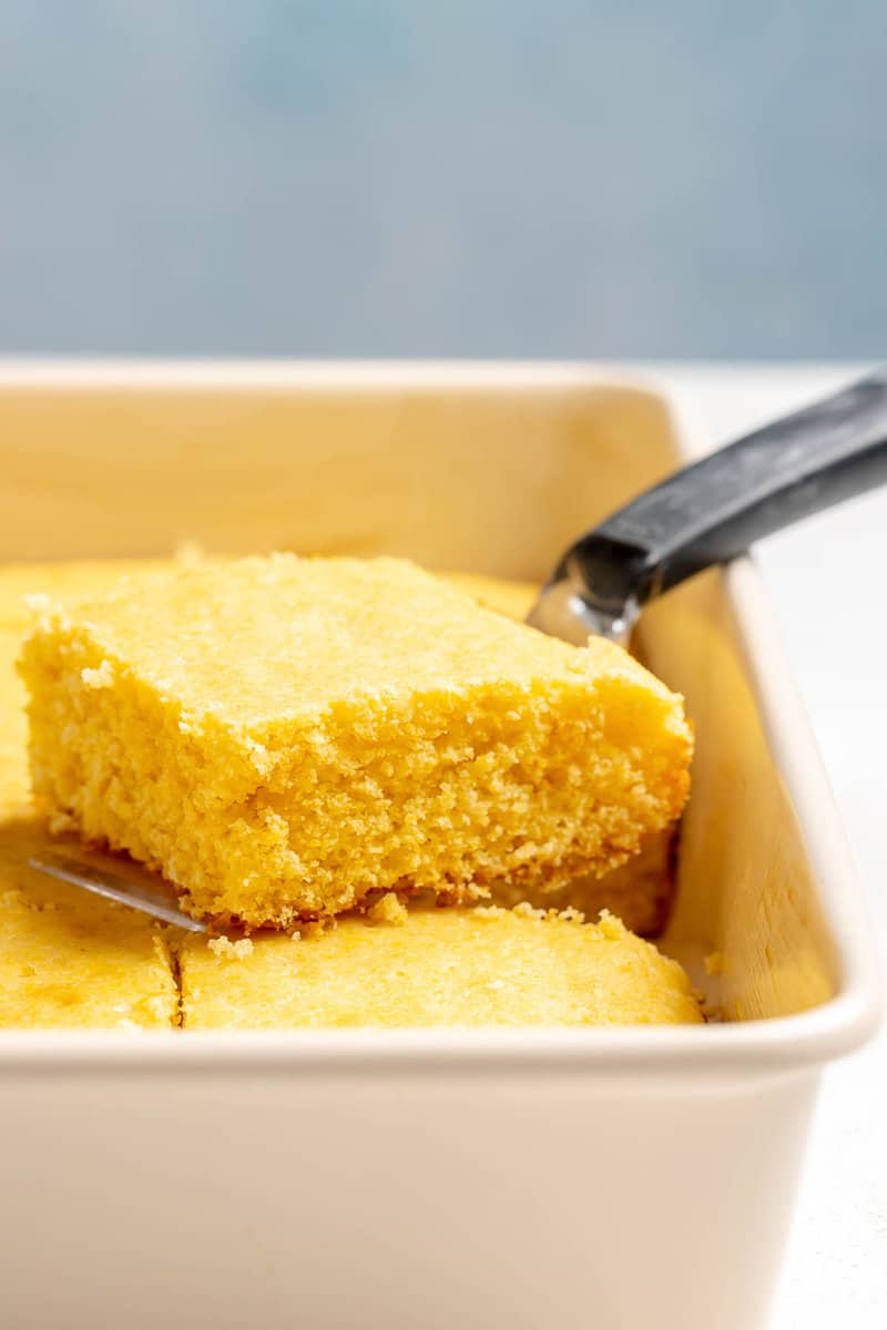 A slice of copycat Tippin's cornbread on a spatula over the pan.