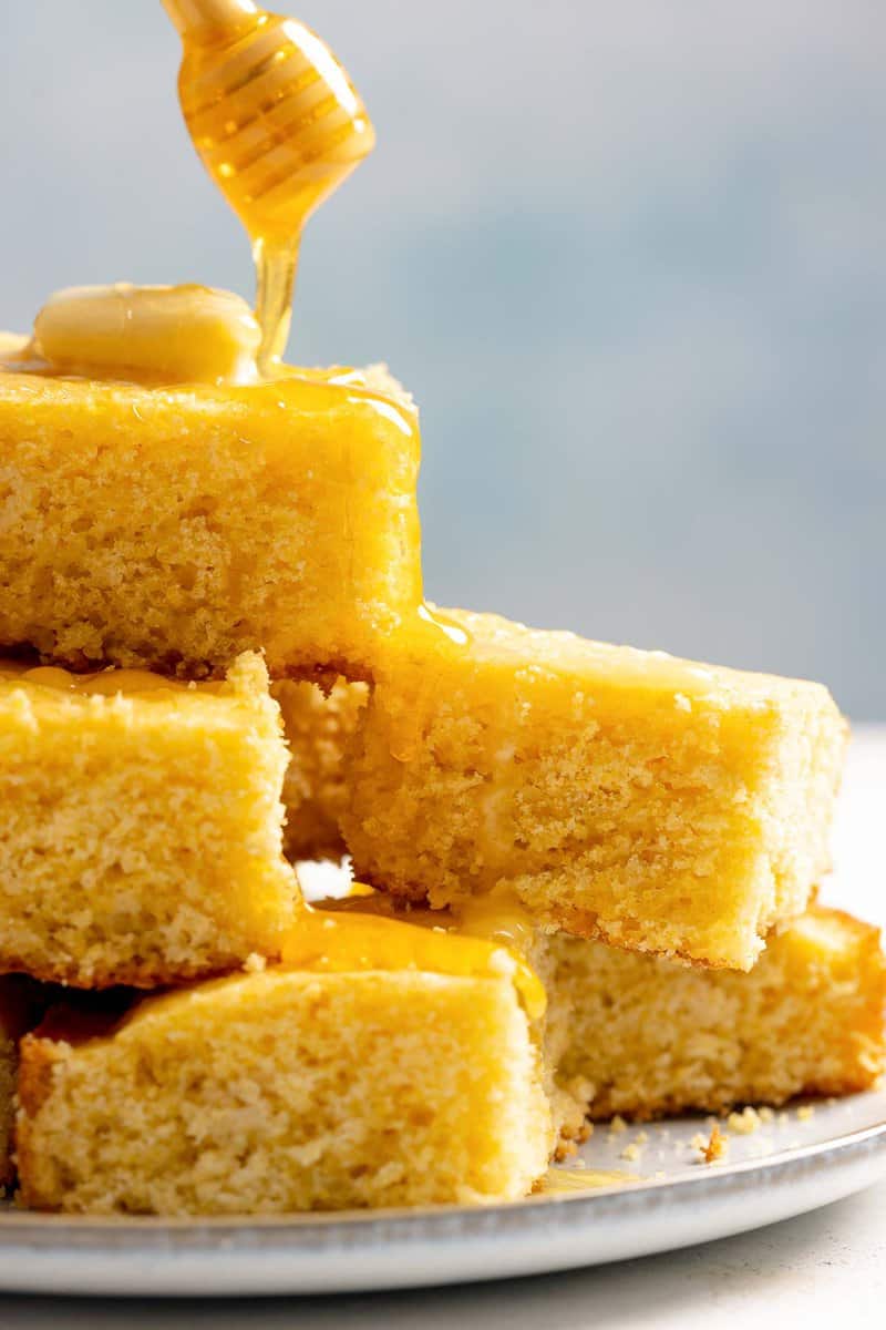 Copycat Tippin's cornbread slices and honey being drizzled over them.