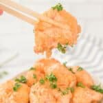 Chopsticks holding an air fryer bang bang shrimp.