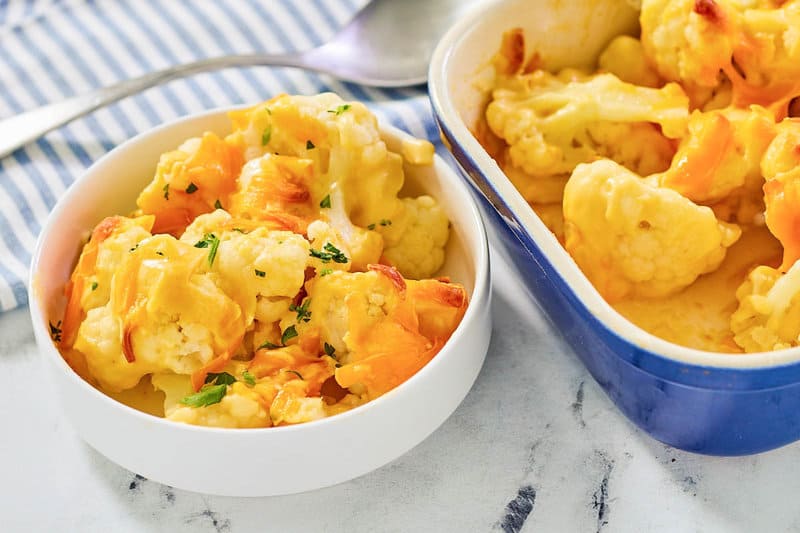 Baked cauliflower with cheese sauce in a bowl and baking dish.