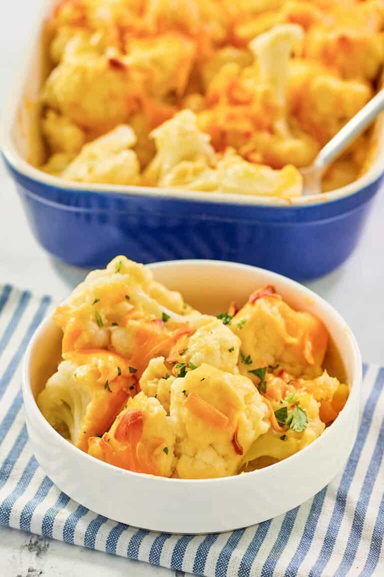 Baked cauliflower with cheese sauce serving in a bowl in front of the dish.