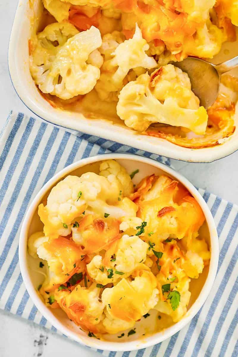 Baked cauliflower with cheese sauce in a baking dish and a serving in a bowl.