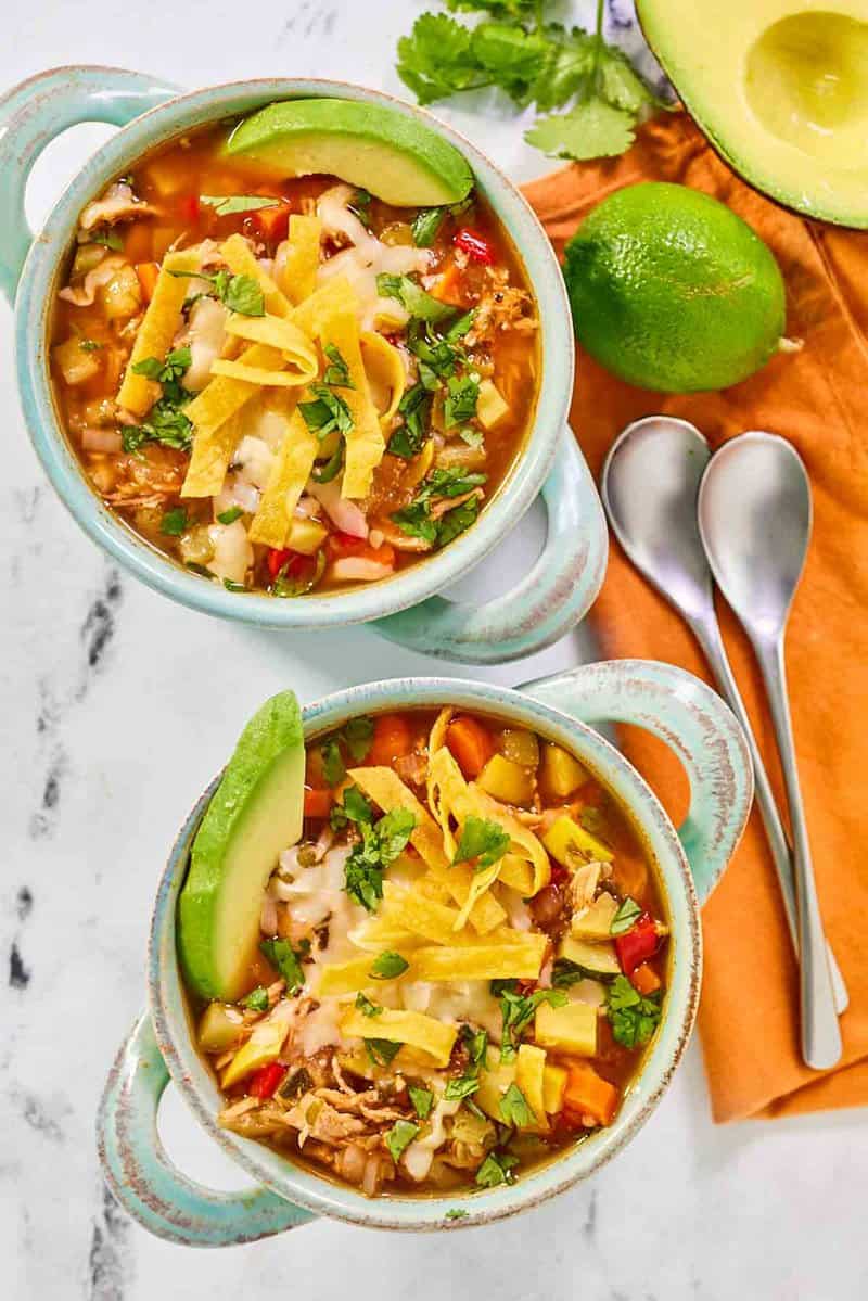 Copycat El Tortio's chicken tortilla soup in two bowls and two spoons.