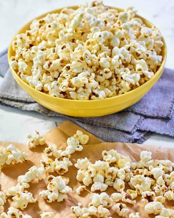 Instant pot popcorn scattered on parchment paper and in a bowl.