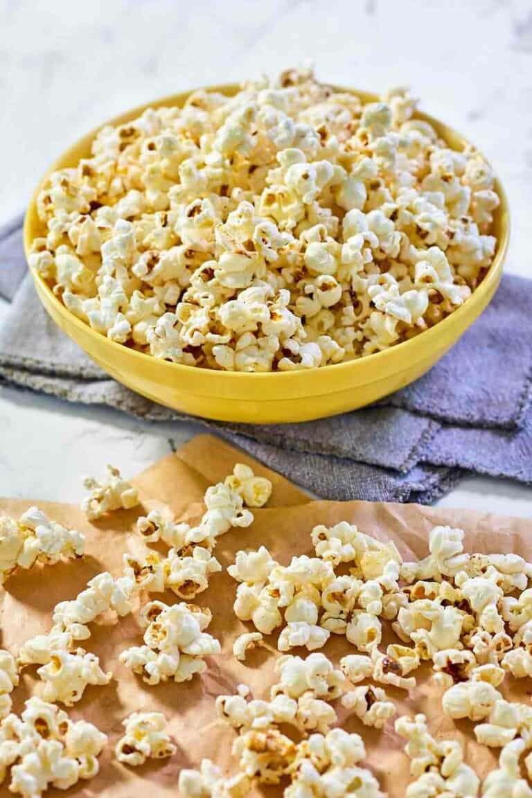 Instant pot popcorn scattered on parchment paper and in a bowl.