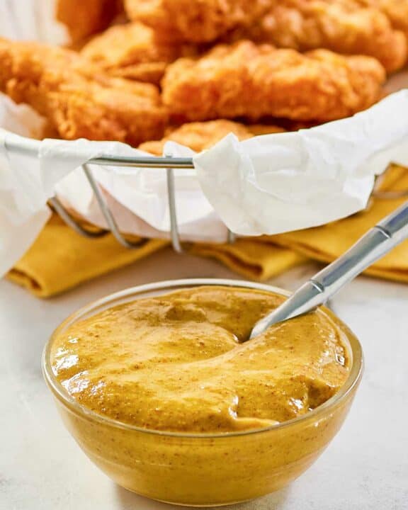 Copycat McDonald's hot mustard sauce in a small bowl and a basket of chicken nuggets.