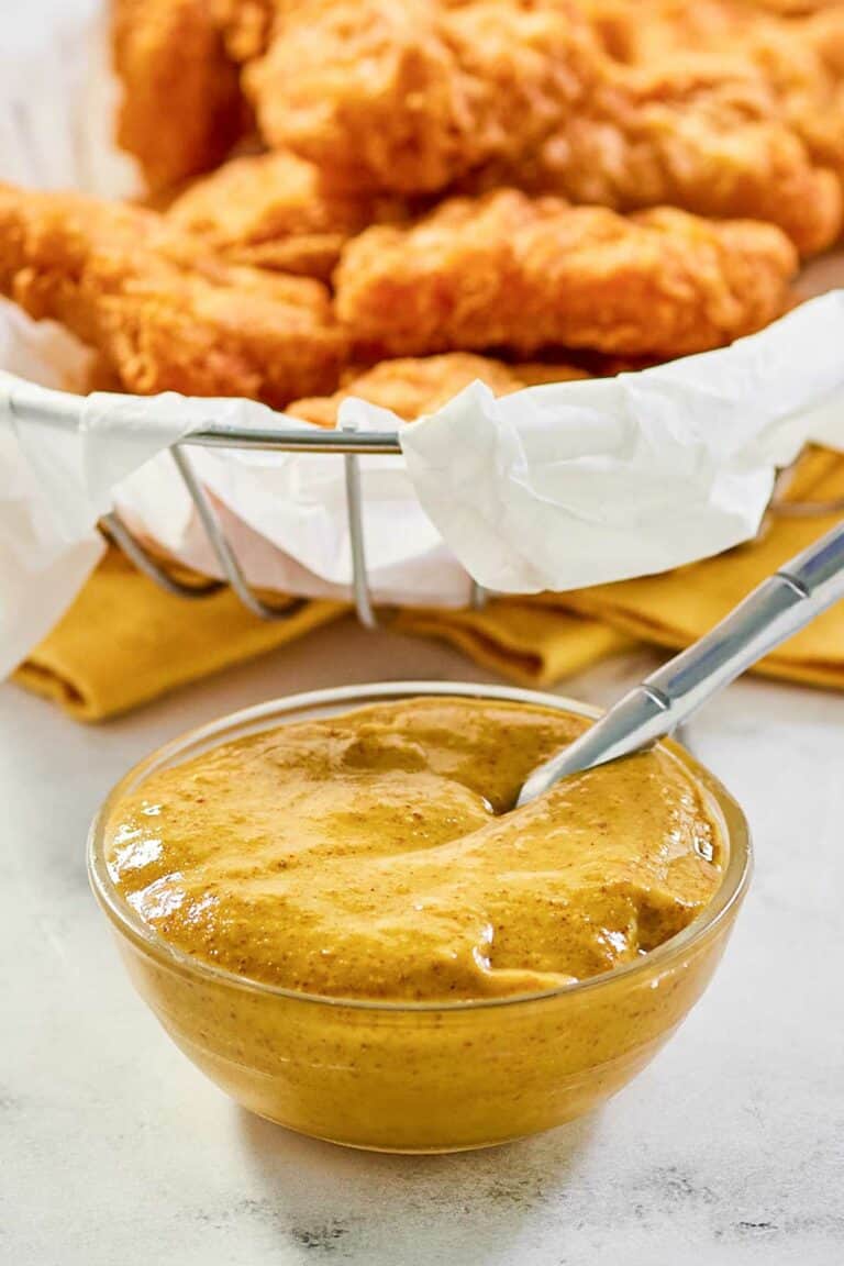 Copycat McDonald's hot mustard sauce in a small bowl and a basket of chicken nuggets.