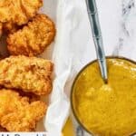 Homemade McDonald's hot mustard in a bowl next to a basket of chicken nuggets.