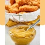 Homemade McDonald's hot mustard sauce in a small bowl and chicken nuggets behind it.