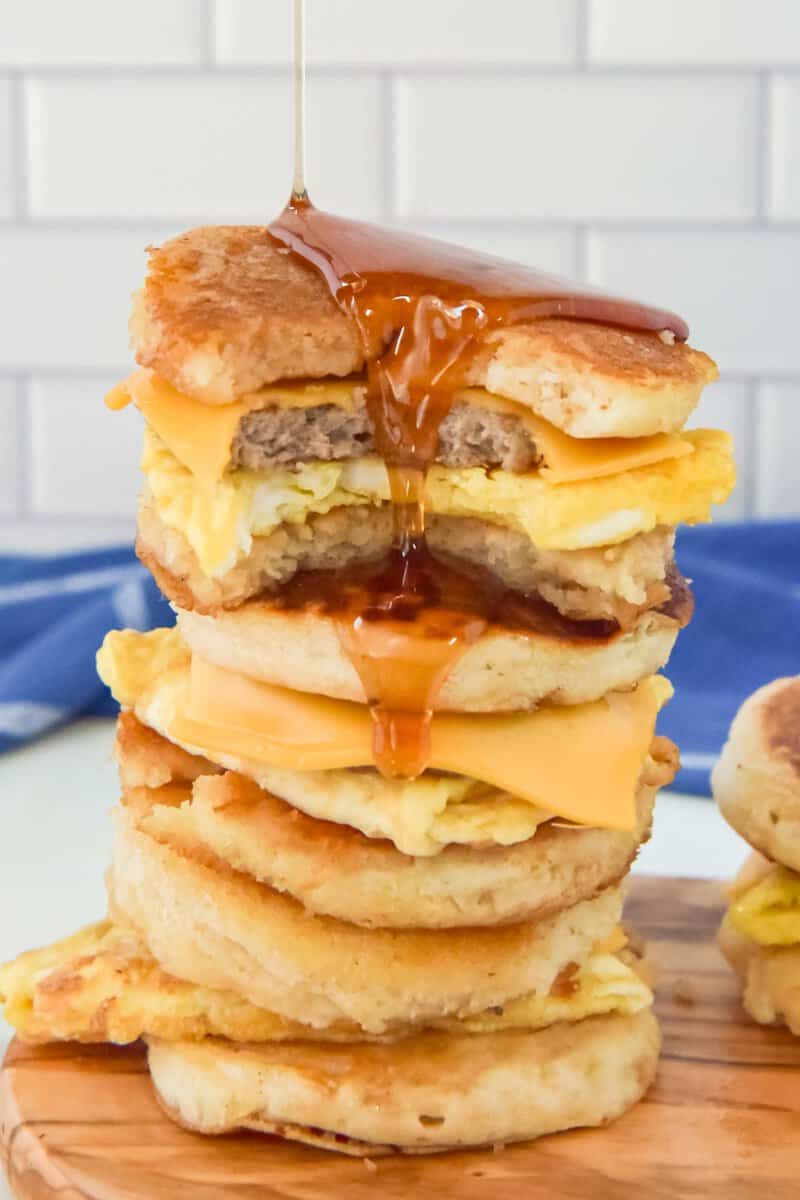 Pouring syrup over a stack of copycat McGriddle sandwiches.