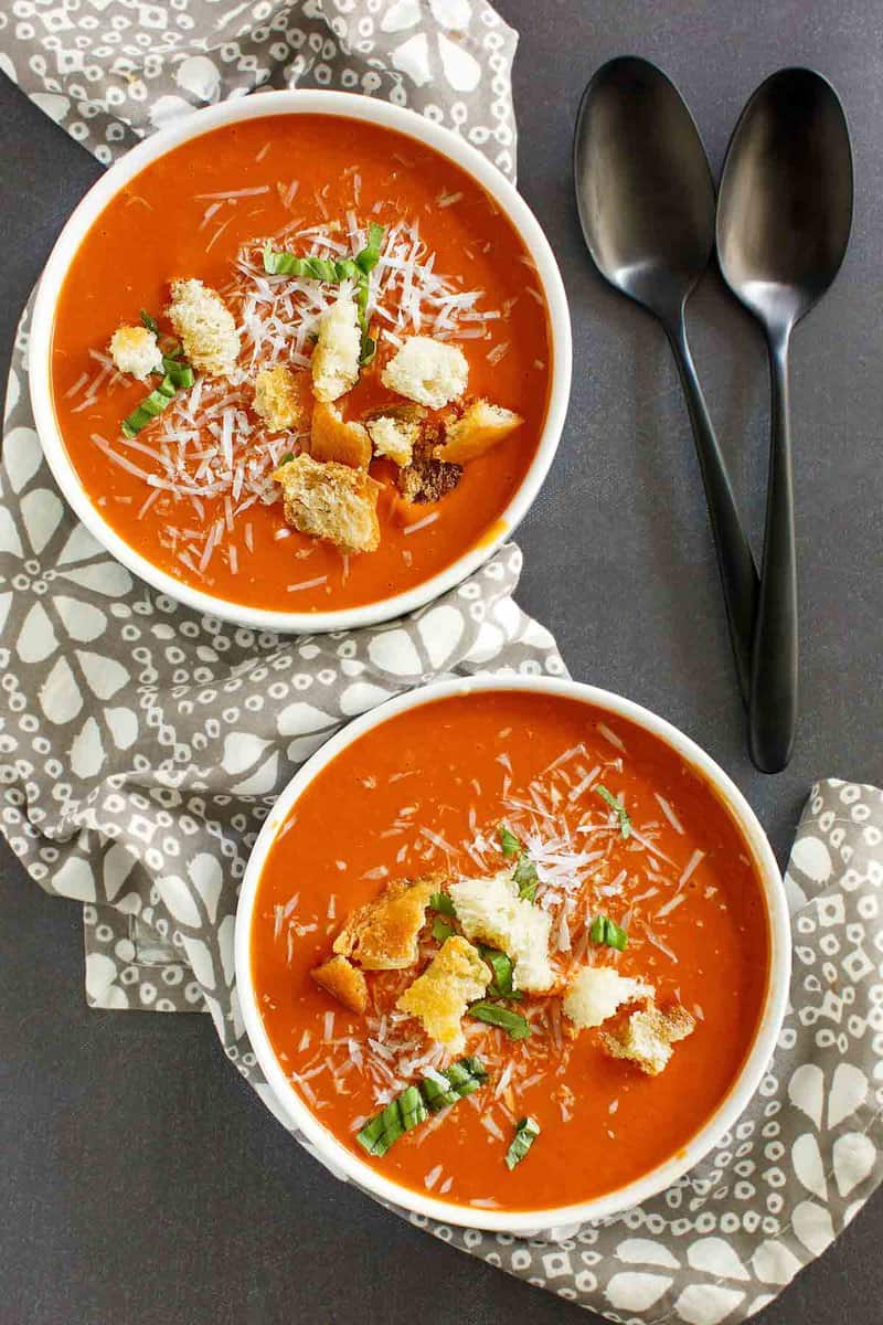 Two bowls of copycat Panera tomato soup and two spoons.